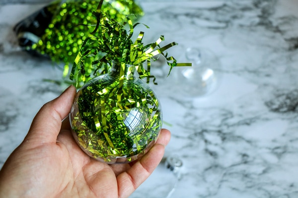 clear christmas ornament filled with green paper for grinch ornament