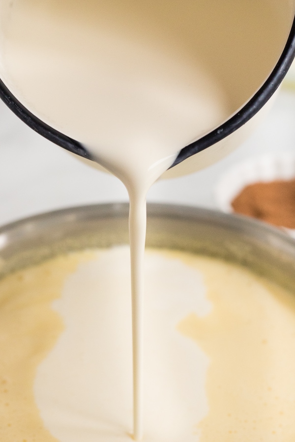 Pouring heavy cream into eggnog holiday recipe