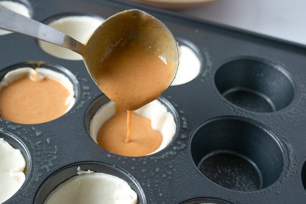 pouring pumpkin pie mix into pie cups for mini pies